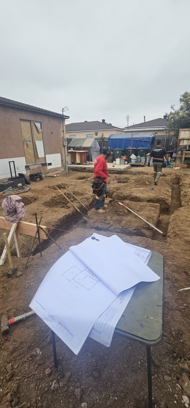Site excavation with blueprints on table and crew working
