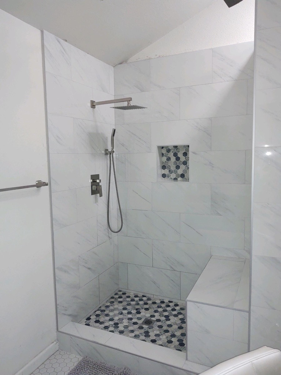 Custom marble walk-in shower with built-in bench and hex pebble floor