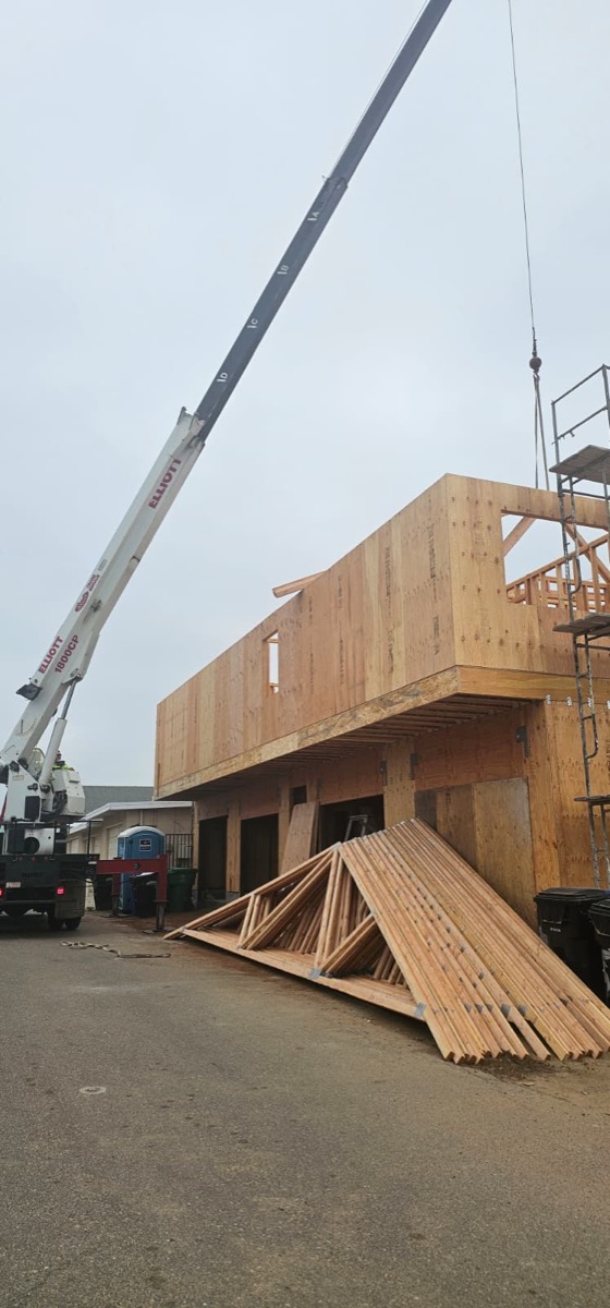 Crane lifting lumber during large-scale home framing