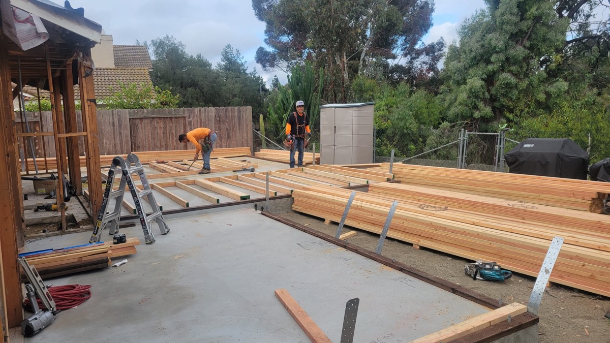 ADU floor framing with lumber and crew laying floor joists