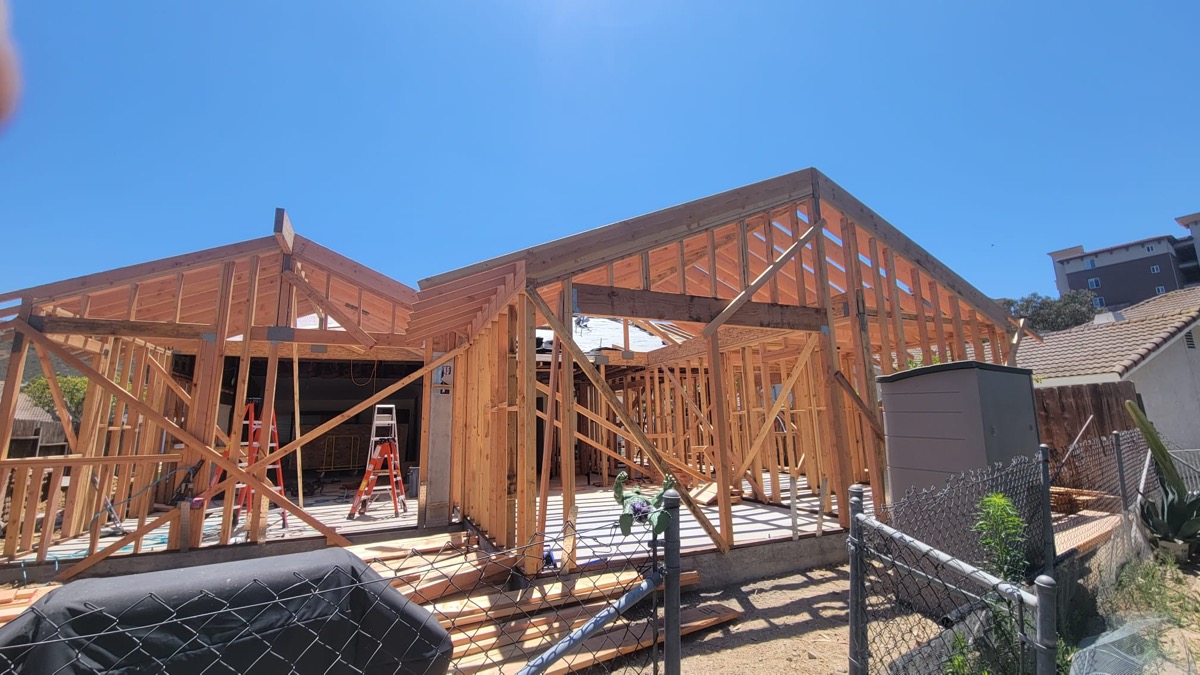 New build framing showing open roof structure and clear blue sky